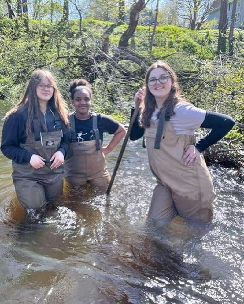 students in waders standing in a river