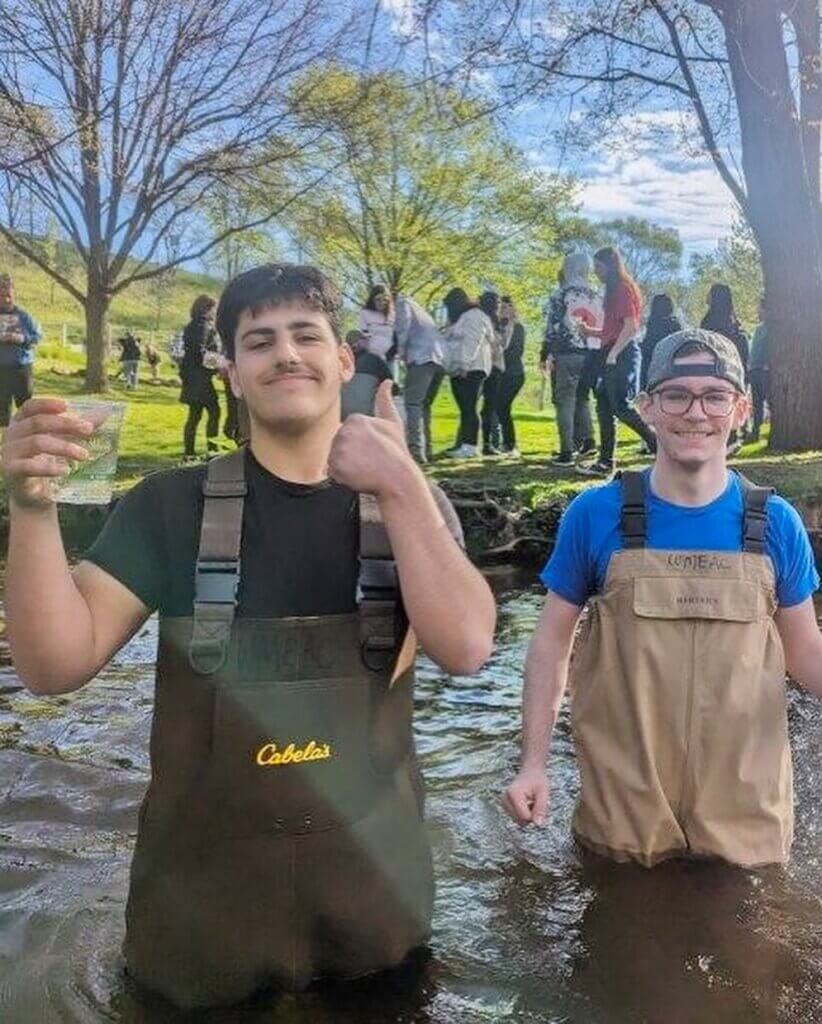 students in waders standing in a river