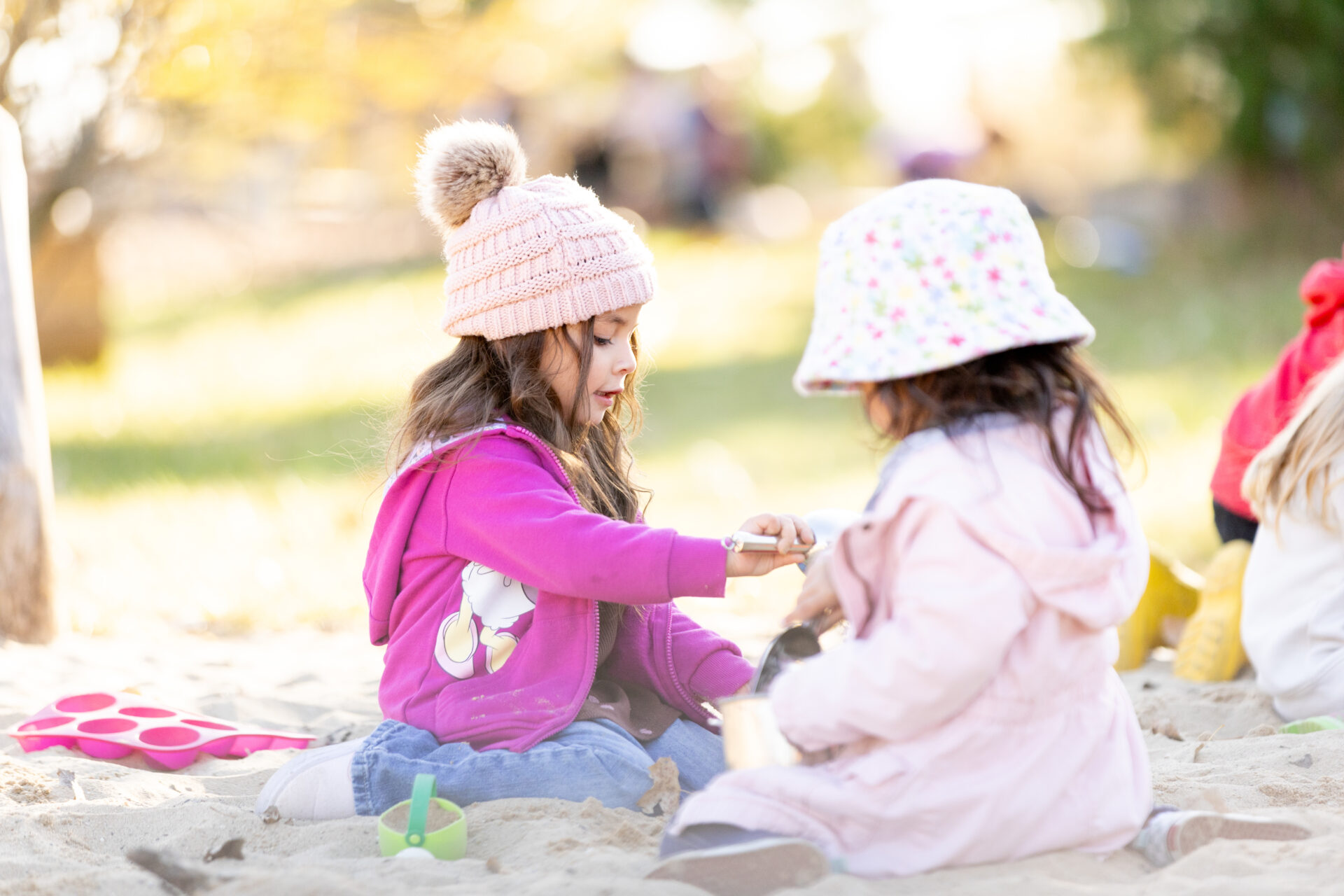 Two young girls play joyfully in the sandy playground, showcasing childhood innocence and friendship.