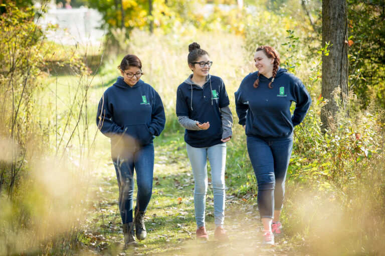 Young women enjoy a joyful walk on a scenic wooded path in autumn.