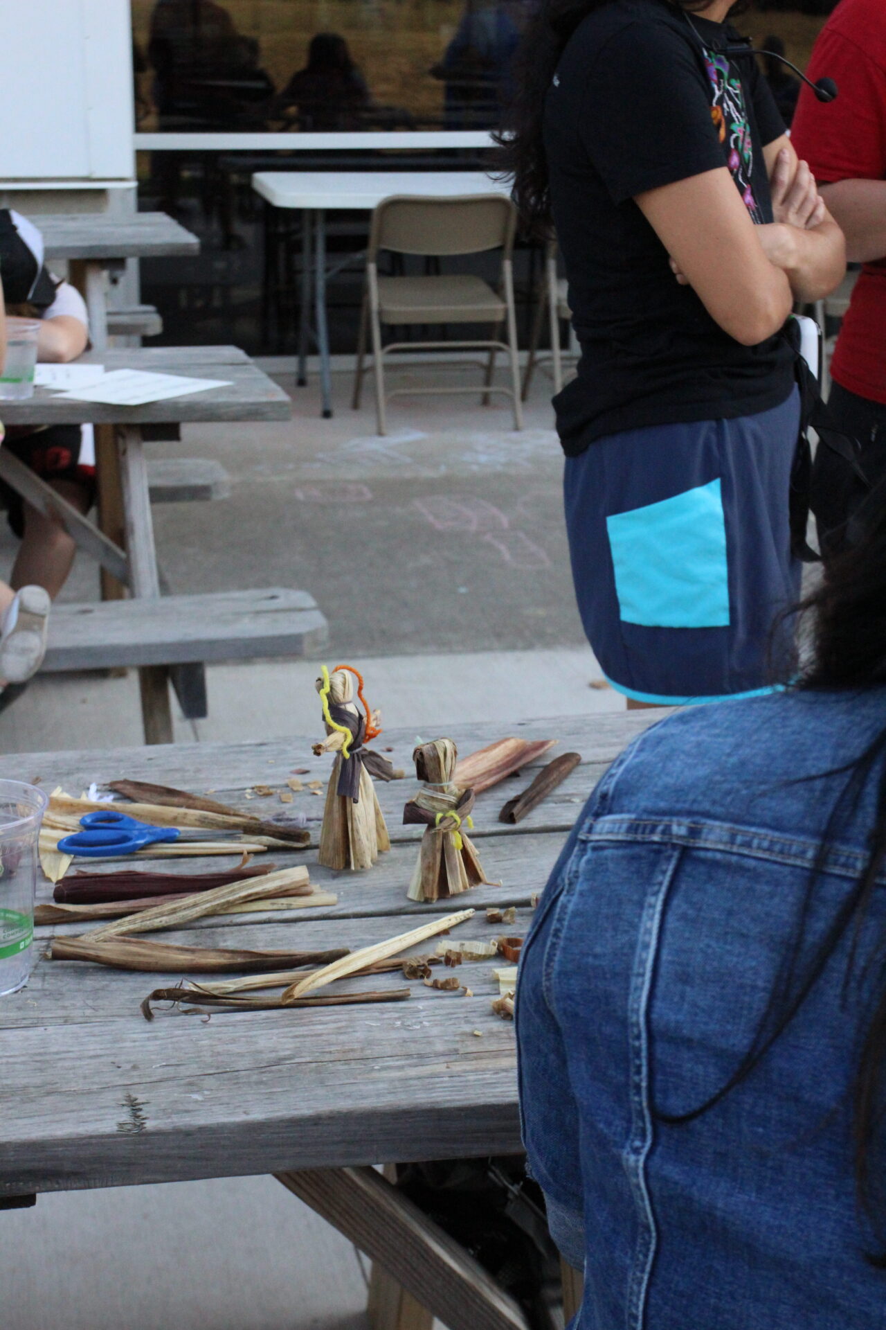 Crafting workshop outdoors with handmade figures, artists engaged in creative activities, and community collaboration.