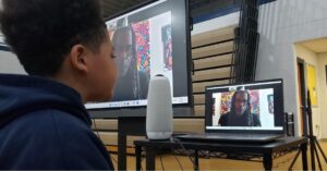 WMAES Student video-calls with Reggie Laurent in the school gymnasium.